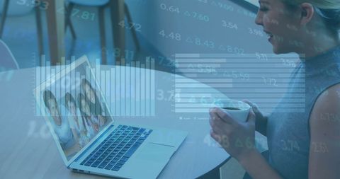 Woman drinking coffee while video calling on laptop with digital interface