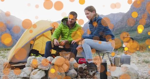 Couple Roasting Marshmallows Camping by Mountain in Bright Outdoor Scene