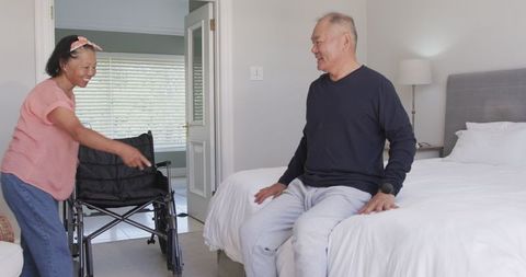 Smiling Female Caregiver Assisting Senior Asian Man at Home