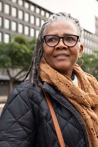 Senior african american woman wearing glasses and scarf looking confident on city street