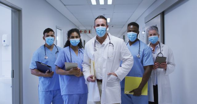 Portrait of diverse group of male and female doctors in face masks standing in hospital corridor - Download Free Stock Photos Pikwizard.com