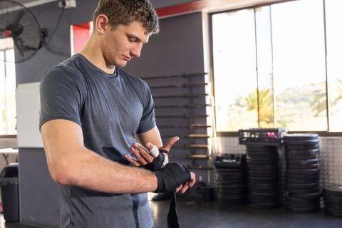 Young man wrapping hands before strength workout showing focus and discipline