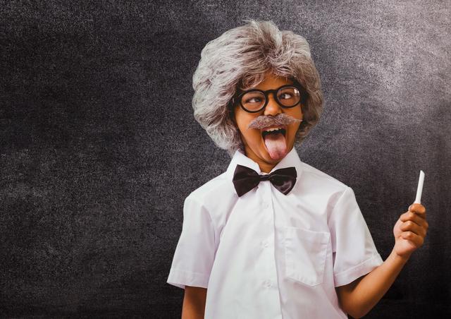 This image depicts a playful school kid in a humorous costume resembling Albert Einstein, holding chalk and posing against a blackboard. The kid is wearing a wig, glasses, and a fake mustache, adding to the comic effect. This photo can be used in educational materials, back-to-school promotions, classroom posters, and fun learning content.