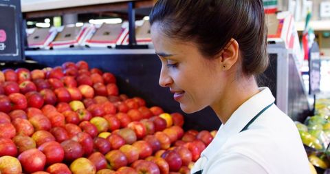 Smiling female staff in organic supermarket fruit section