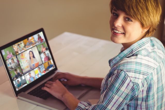 Young woman smiling during a virtual meeting on a laptop. Great for illustrating remote work, online conferencing, digital teamwork, communication through technology, and the modern work-from-home environment. Ideal for articles on remote workplace dynamics, virtual collaboration tools, and online networking events.