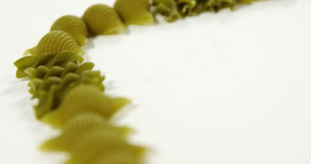 Close-Up of Green Pasta in Curved Arrangement on White Background - Download Free Stock Images Pikwizard.com