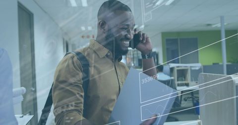 Smiling Businessman with Data Overlay Talking on Smartphone in Office
