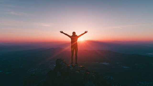 Hiker Celebrating Sunrise on Mountain Peak with Open Arms