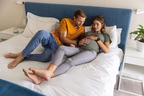 Expectant Couple Relaxing on Bed in Modern Bedroom