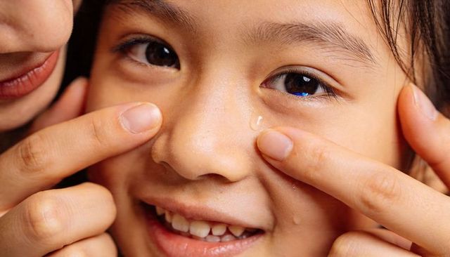 Tender close-up of parent touching child cheek smiling with tear and warm affection