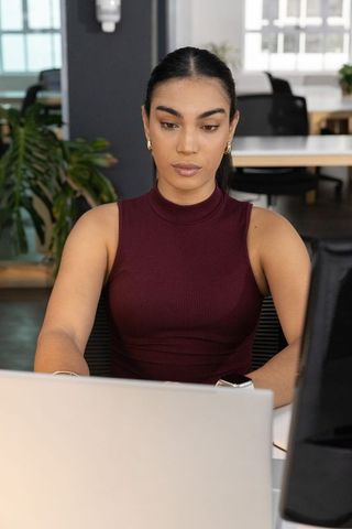 Focused professional woman typing on laptop in modern open-plan office