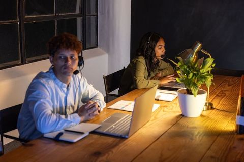 After-hours customer support team working on laptops at communal wooden desk