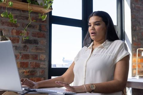 Woman In Office Using Laptop With Surprised Expression