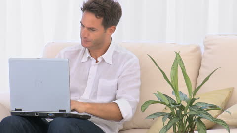 Frustrated Man Using Laptop on Sofa at Home