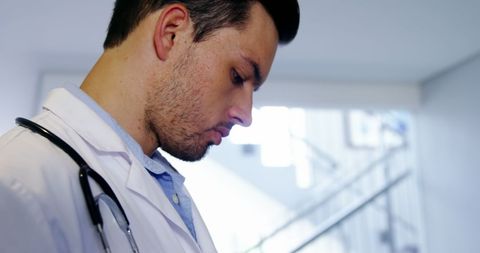 Male Doctor Using Digital Tablet in Hospital Corridor