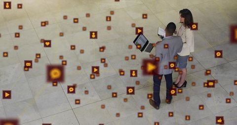 Business professionals collaborating over laptop with floating social media network icons