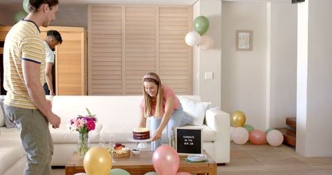 Friends celebrating new job with cake in bright living room