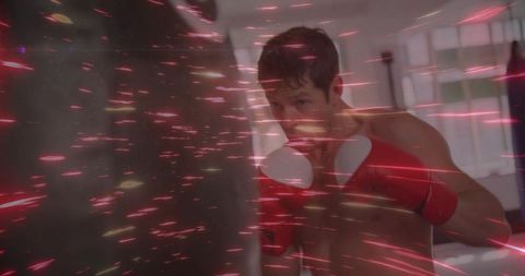 Shirtless boxer punching with red gloves and dynamic light streaks in gym
