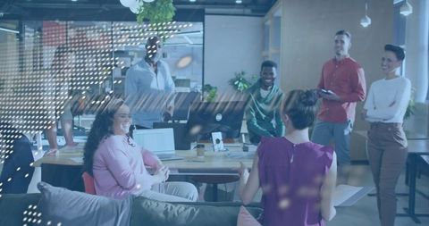 Multicultural team brainstorming around desk with laptops in bright modern open-plan office