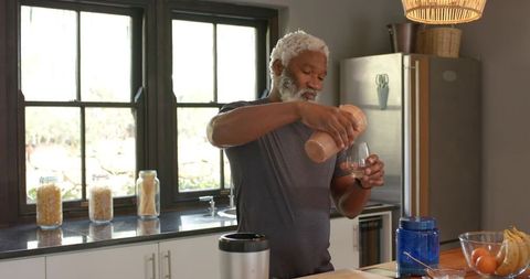 Senior man making cocoa shake in modern kitchen for healthy living