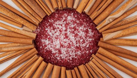 Cinnamon stick sunburst surrounding red and white salt crystals, top view closeup