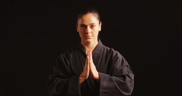 Karate player in prayer pose against black background