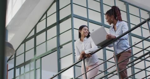 Diverse Businesswomen Collaborating on Laptop in Modern Office Setting