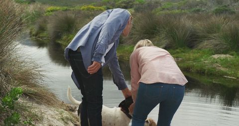 Senior Couple Enjoying Nature with Dog by Riverside