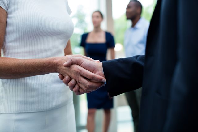 Business executives shaking hands, symbolizing partnership and successful deal. Ideal for use in business presentations, corporate websites, networking events, and articles about professional collaboration and teamwork.