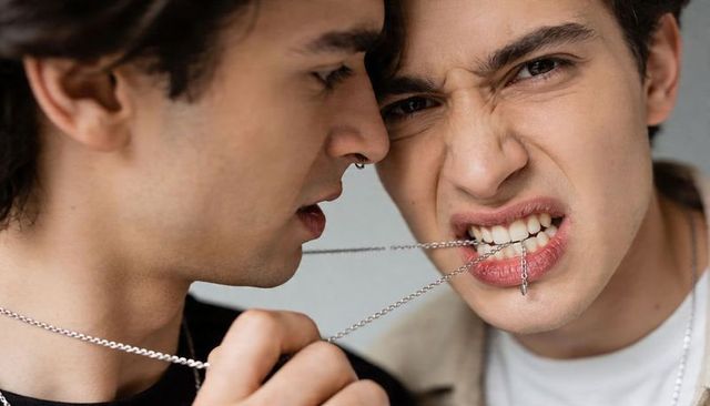 Teen tension tugging silver chain between teeth closeup conveying rebellion and conflict