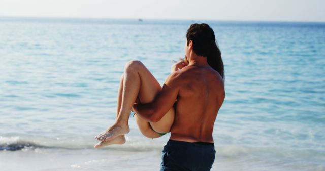 Couple cherishing romantic moments at the sunlit beach. Ideal for use in advertisements for travel agencies, vacation packages, lifestyle blogs, or any marketing materials related to romance and travel destinations. Highlights themes of love, summer joy, and togetherness.