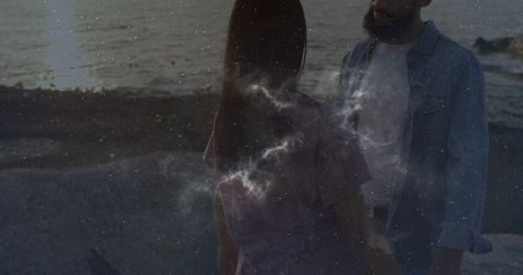 Couple on rocky shore at dusk with cosmic theme