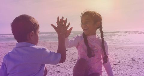 Joyful Siblings Sharing High Five at Beach