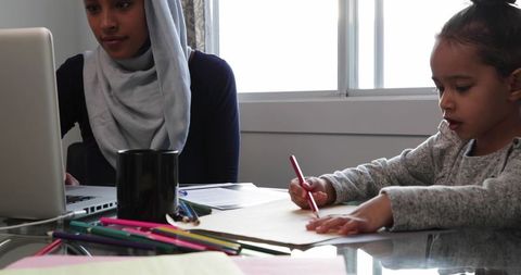 Busy Mother Working on Laptop with Daughter Coloring