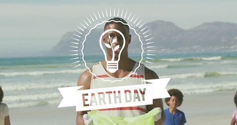 Volunteer holding green trash bag on sunny beach picking litter for earth day cleanup