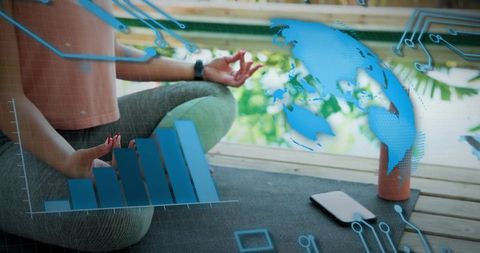 Practicing mindfulness yoga on outdoor deck with smartwatch, AR wellness graphs and globe