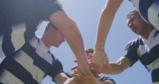 Football players in a tight huddle with hands together demonstrating teamwork and unity. Ideal for images representing sportsmanship, teamwork activities, outdoor sports events, or team-building efforts. Can be used in promotional materials for sports clubs, motivational posters, or coaching tutorials.