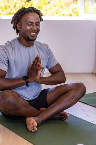 African american man meditating on yoga mat practicing mindfulness and wellness at home