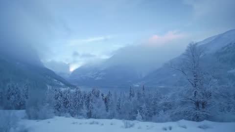 Sunbeam Piercing Snowy Alpine Valley at Dawn with Misty Mountains and Frosted Pines