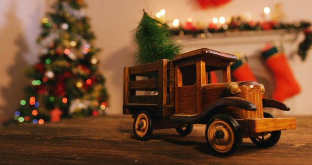 Set during the festive season, a vintage toy truck carrying a tiny Christmas tree adds a touch of nostalgia. The background shows a blurred decorated Christmas tree, string lights, and stockings hung over a mantle. This can be used to evoke cozy, nostalgic holiday feelings, perfect for ads, social media posts, or holiday greeting cards.