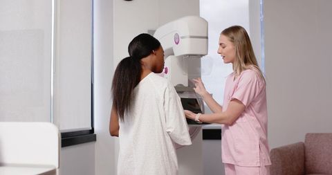 Diverse Female Patient Receiving Mammogram with Technologist Guiding Positioning