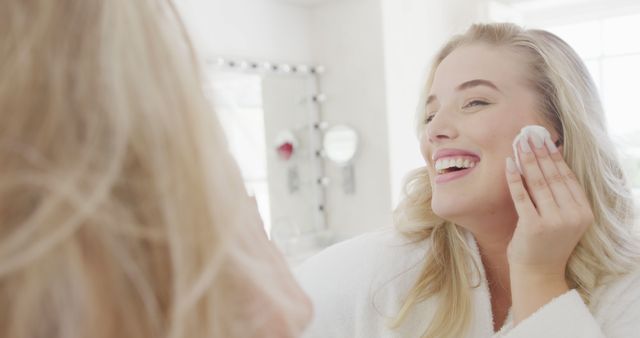 Smiling Woman Cleansing Face While Looking in Mirror in Bright Bathroom - Download Free Stock Images Pikwizard.com