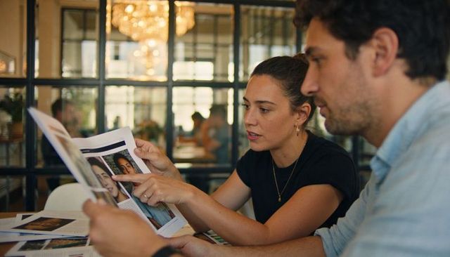 Creative team reviewing headshots and layouts in modern open office with glass partition