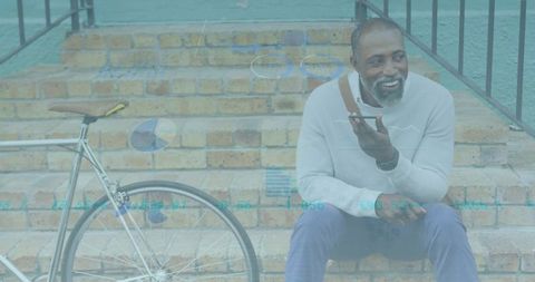 Mature man sitting on brick steps speaking into smartphone with bicycle and data overlays
