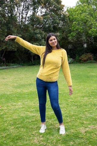 Woman in Yellow Sweater Stretching on Green Lawn