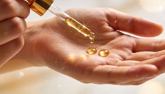 Golden facial serum droplets on palm with dropper highlighting luxury skincare