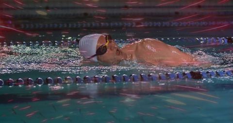 Competitive swimmer gliding through pool freestyle with dynamic light reflections, motion