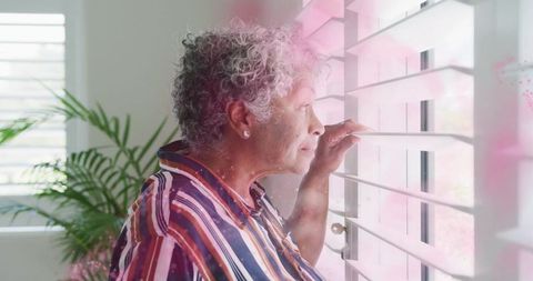 Serene Senior Woman Enjoying View Through Window Blinds