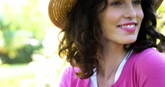 Smiling woman wearing sun hat enjoying a sunny day outdoors with natural background. Perfect for promoting summer fashion, outdoor activities, health and wellness, travel, and lifestyle blogs.
