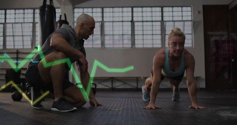 Trainer Coaching Female Athlete Performing Plank with Heart Rate Overlay in Functional Gym